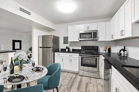 A kitchen with a table set for two and a refrigerator.