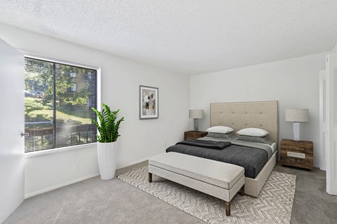 A bedroom with a large bed and a potted plant.