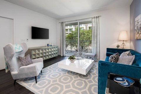 A living room with a grey chair, a white coffee table, and a blue couch.