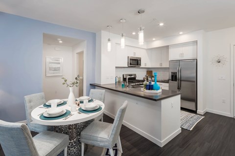 A modern kitchen with a dining table set for two.
