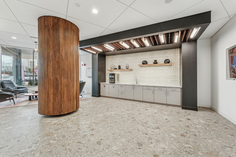 A modern office lobby with a wooden column and a row of lockers.