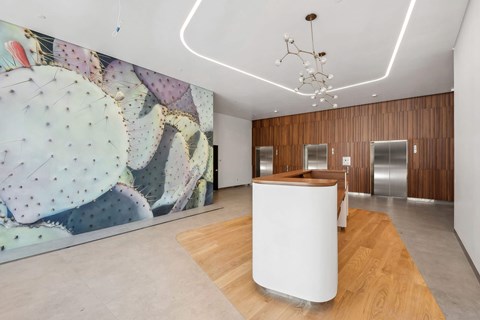 A room with a white reception desk and a cactus mural on the wall.