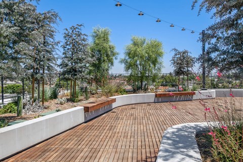 A wooden deck with a bench and trees in the background.