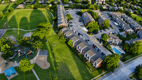An aerial view of a residential area with houses, a park, and a playground.