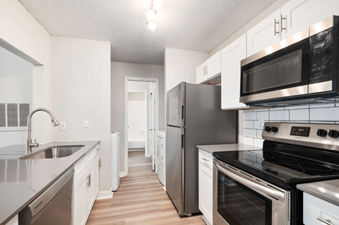 A kitchen with white cabinets and black appliances.