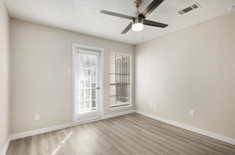 A room with a ceiling fan and a door leading to a balcony.