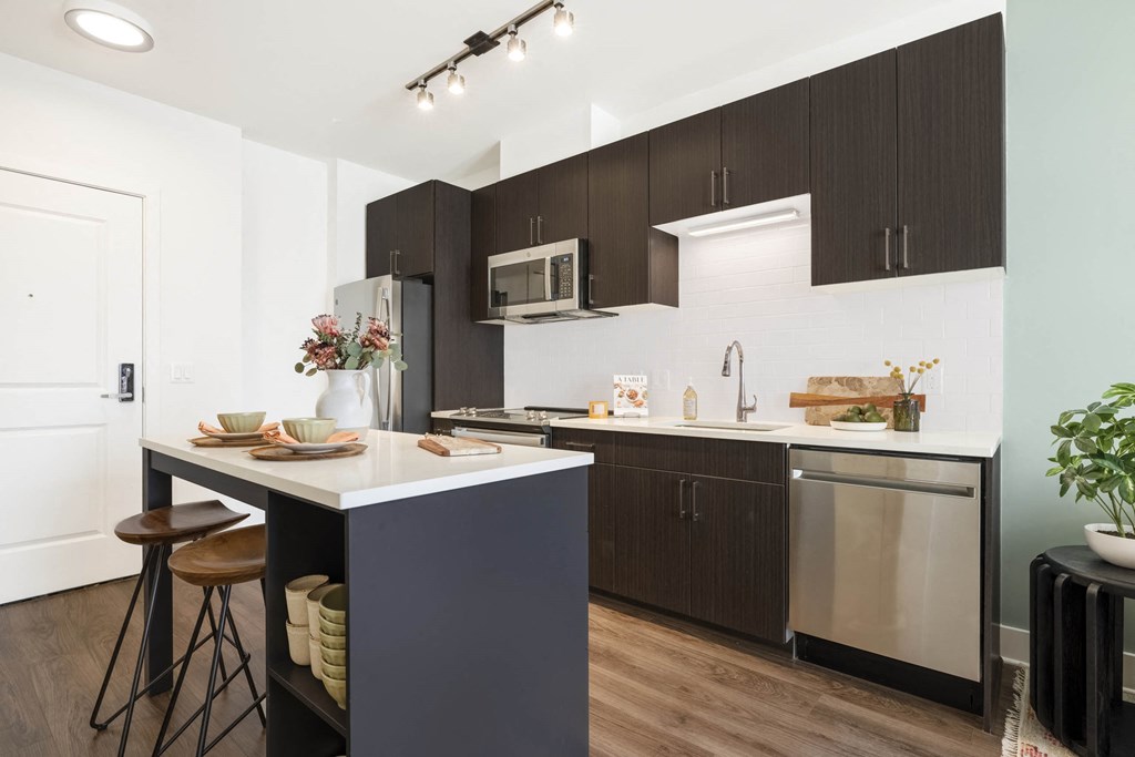 A kitchen with a white counter top and brown cabinets.at The Vale at the Parks, Washington, DC  