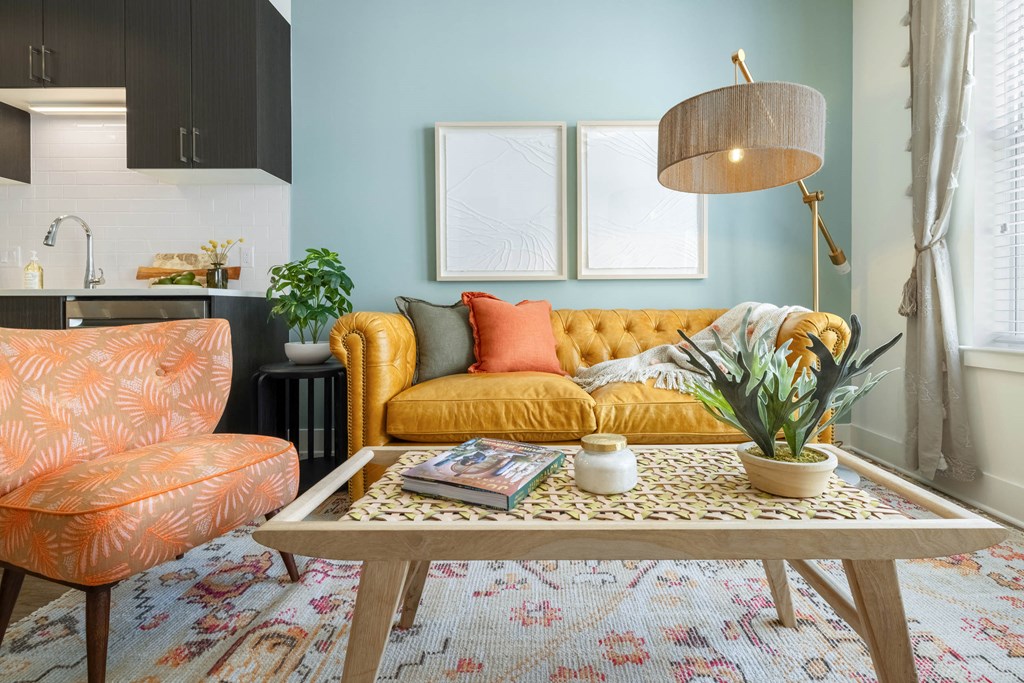 A living room with a yellow sofa, a patterned rug, and a wooden coffee table.at The Vale at the Parks, Washington, DC  