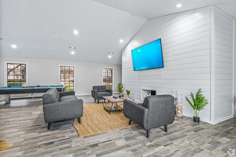 A living room with a pool table and a television mounted on the wall.