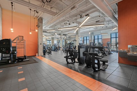 A gym with orange walls and black equipment.