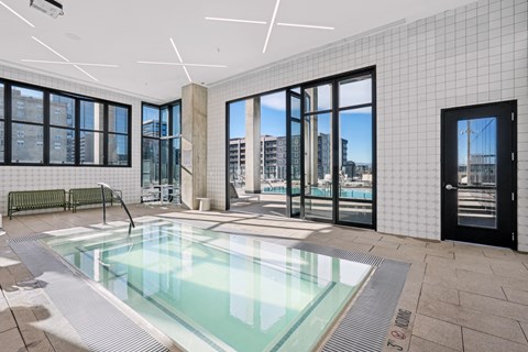 A swimming pool inside a building with a view of the city.