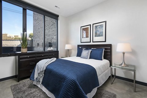 A bedroom with a large bed and a window overlooking the city.