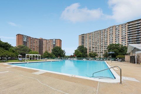 A swimming pool in a sunny day surrounded by buildings.