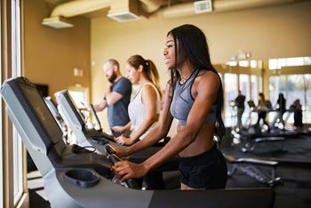 A woman is running on a treadmill in a gym at Coro Apartments, Los Angeles, 90016