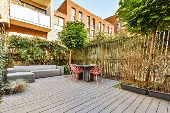 A wooden deck with a table and chairs in the middle of a backyard at Coro Apartments, California