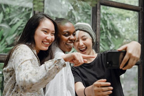 Three people taking a selfie with a smartphone.