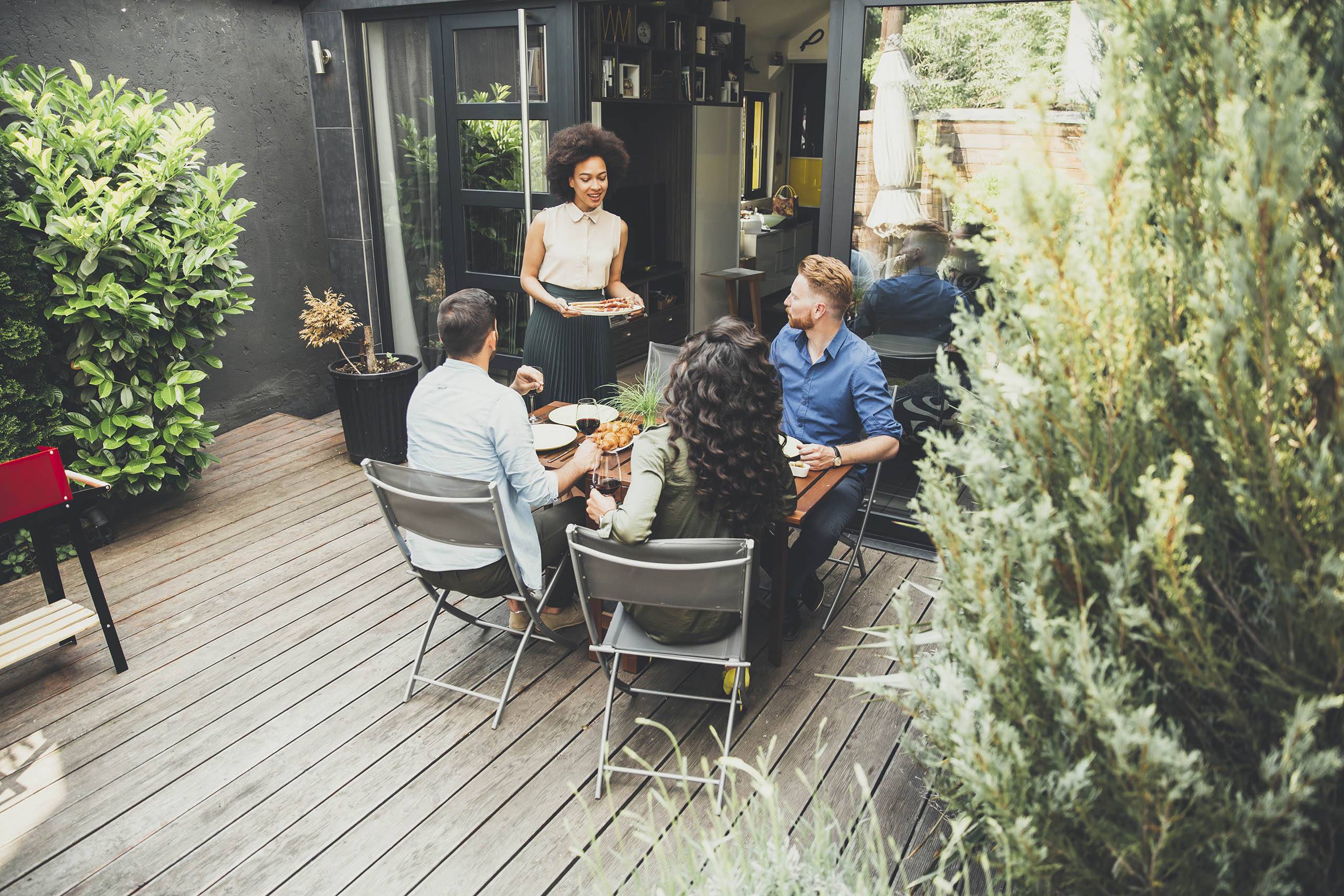 A group of people are sitting around a table on a wooden deck.