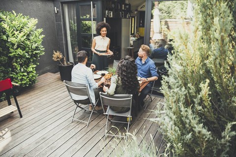 A group of people are sitting around a table on a wooden deck.