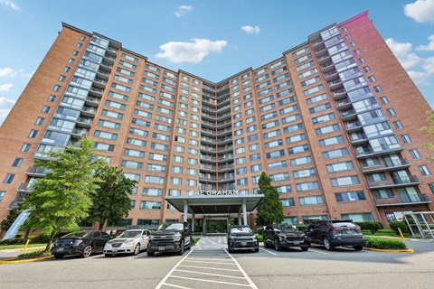 A large red brick hotel with a parking lot in front.