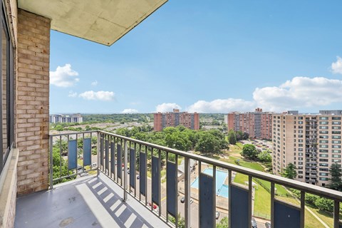 A balcony with a view of a pool and buildings.