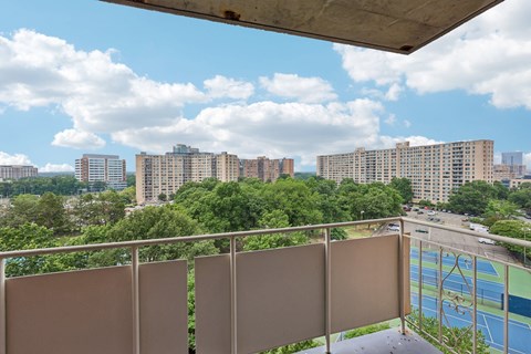 A balcony with a view of a cityscape and a pool.