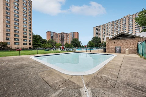 A swimming pool in a concrete pool area with buildings in the background.