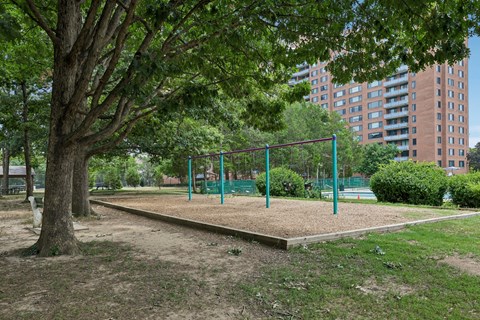 A playground with a green fence and a sandbox.