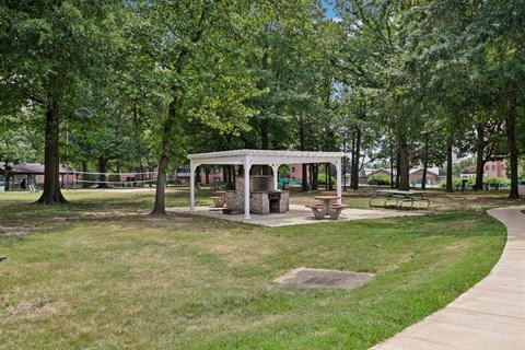 A pavilion in a park with a picnic table and chairs.