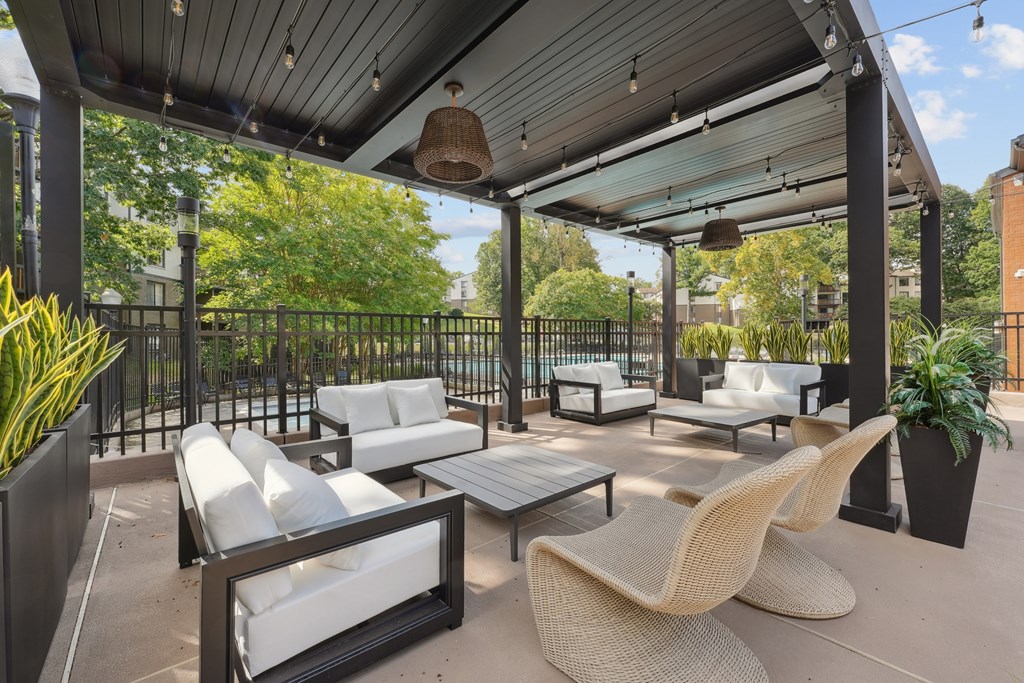 A patio with white cushioned furniture and a black metal fence.