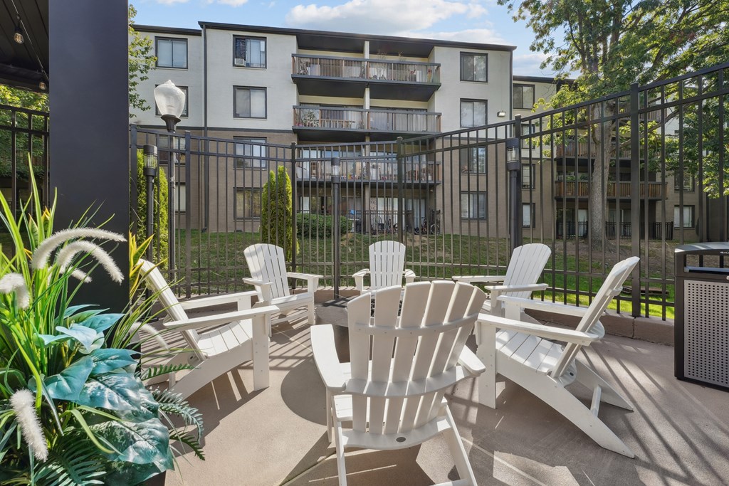 A patio with white chairs and a table is in front of a building.