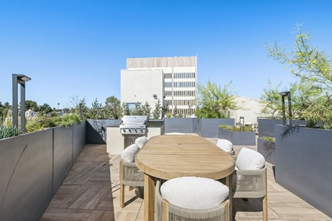 A wooden table with four chairs is set up on a wooden deck at 1915 Park, Los Angeles, CA 90026