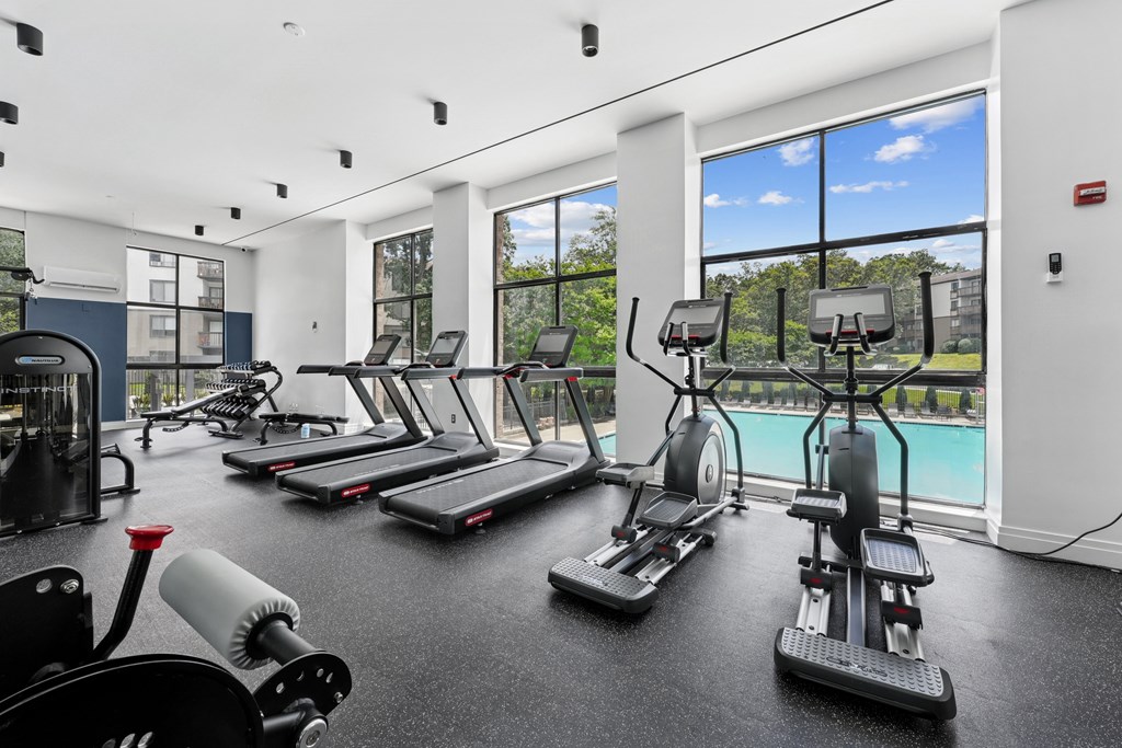 A gym with treadmills, elliptical machines, and weights.