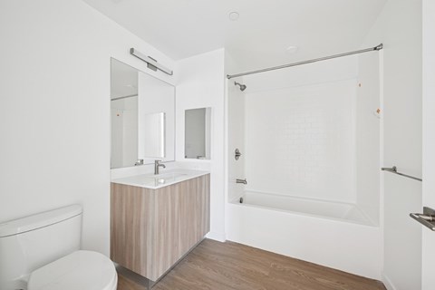 A white bathroom with a wooden vanity and a walk-in shower at 1915 Park, Los Angeles, CA 90026