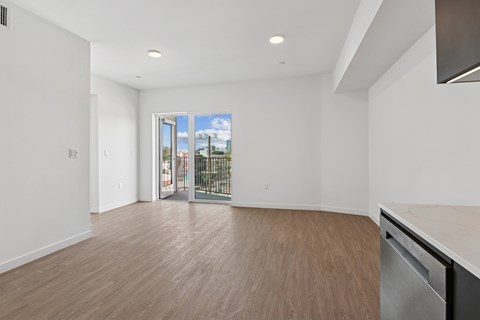 A large empty room with a stainless steel dishwasher and wooden flooring.