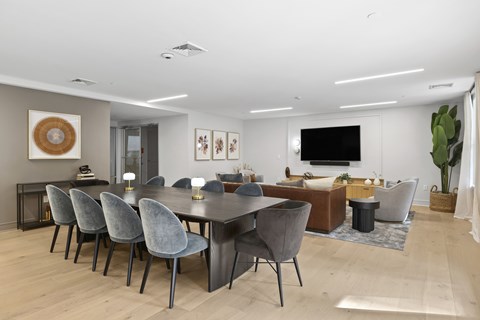 A modern dining room with a large table and grey chairs.