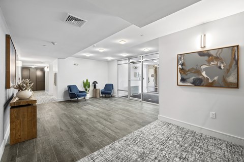 A spacious hallway with a large painting on the wall and two blue chairs.