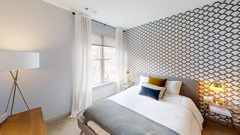 A bedroom with a large bed and a patterned wallpaper.