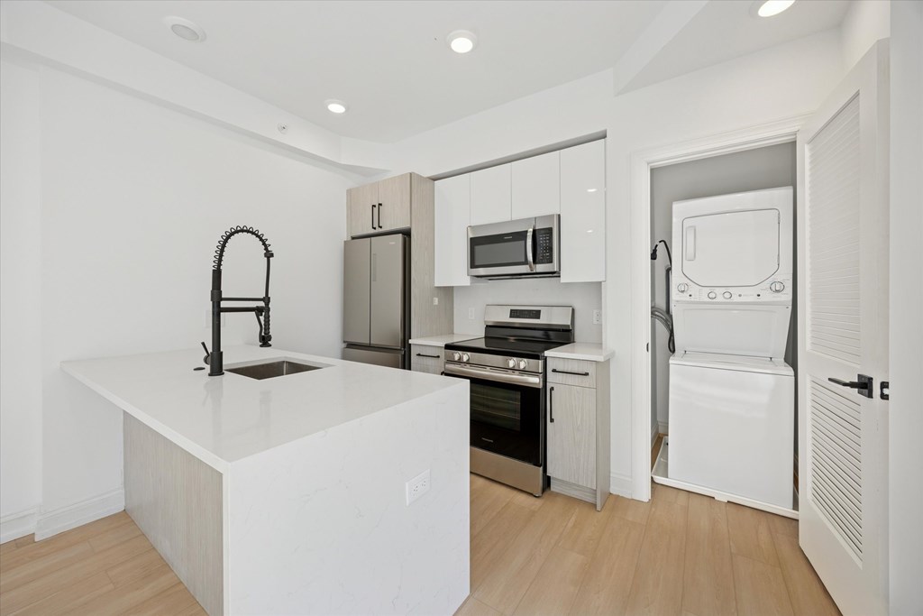 A kitchen with white appliances and a white island.