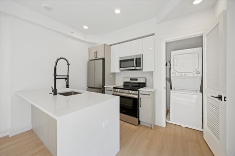 A kitchen with white appliances and a white island.