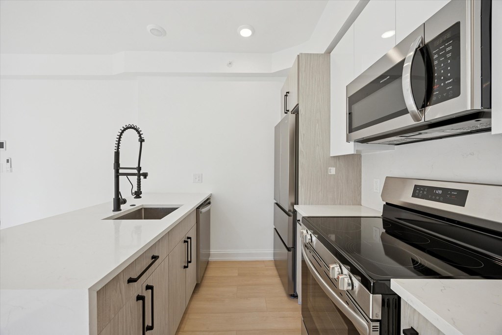 A modern kitchen with a sink, stove, and microwave.