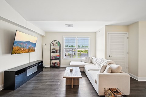 A living room with a white couch and a painting on the wall.
