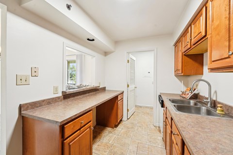 A kitchen with brown cabinets and a tiled floor.