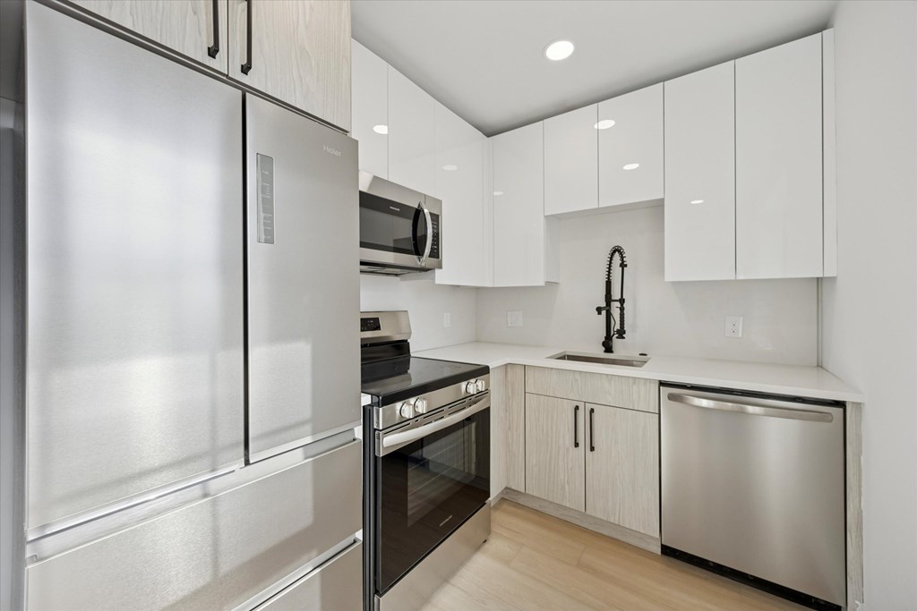 A modern kitchen with stainless steel appliances and white cabinets.