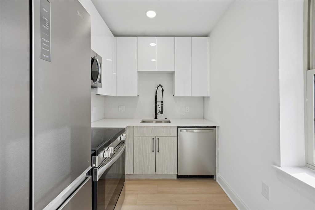 A modern kitchen with a stainless steel refrigerator and a dishwasher.