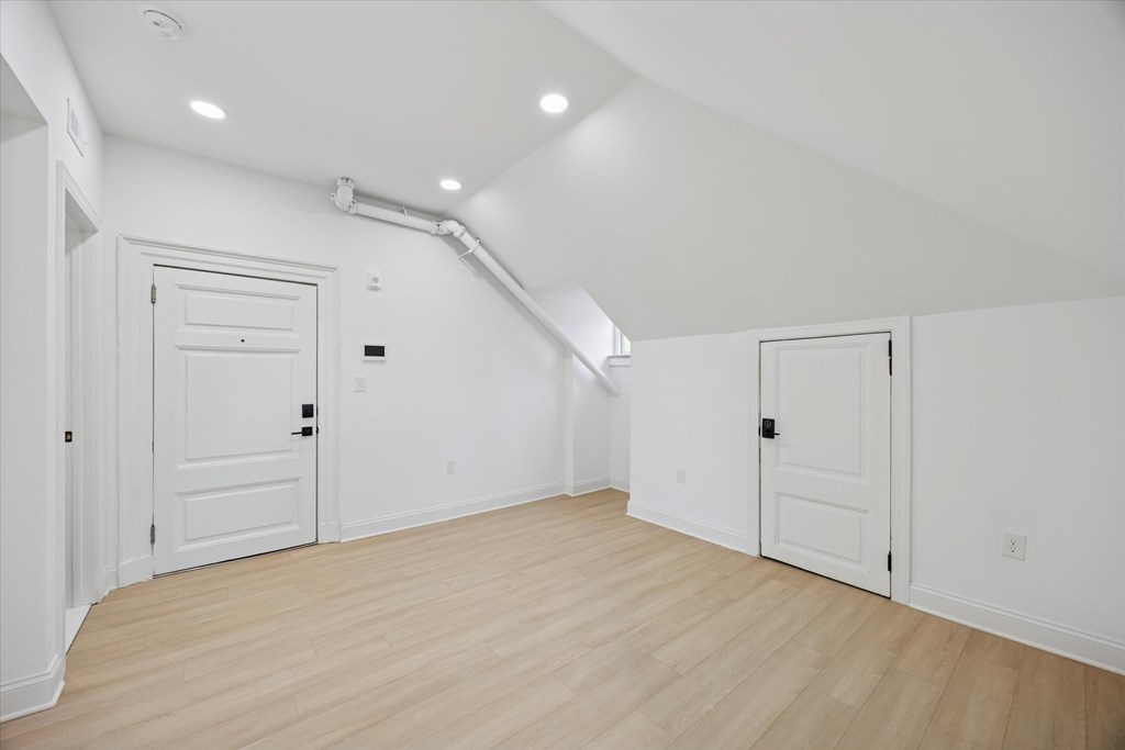 A white room with wooden floors and two doors.
