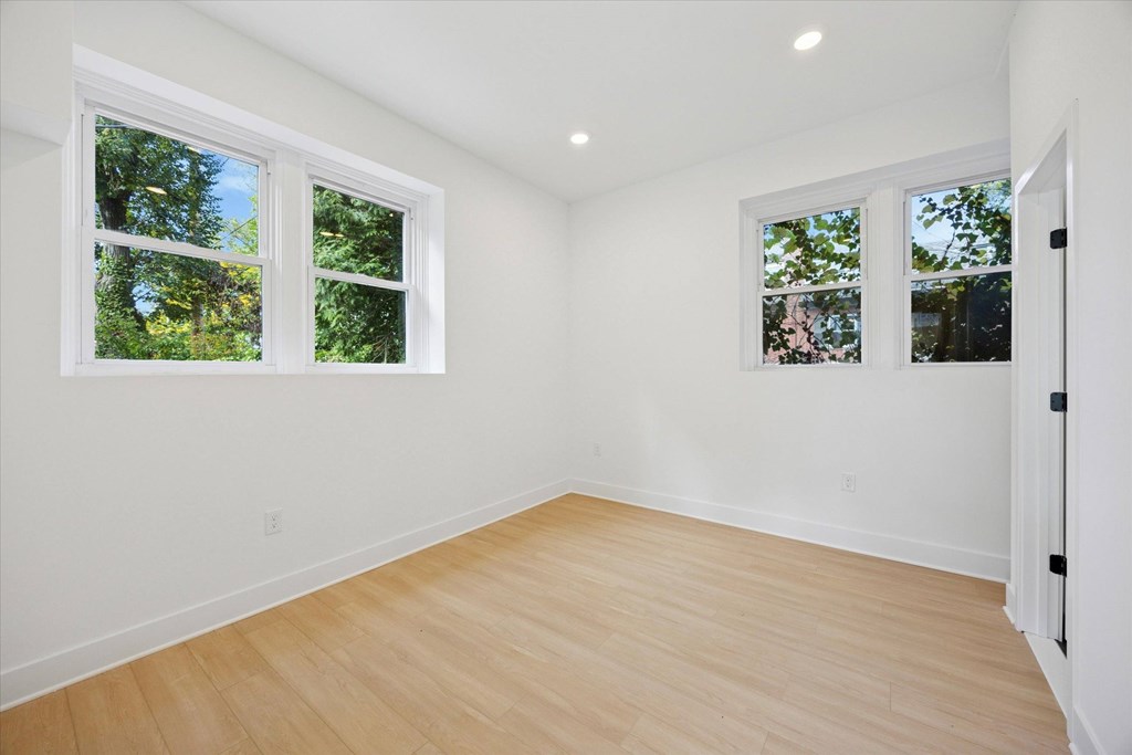 A room with two windows and wooden flooring.