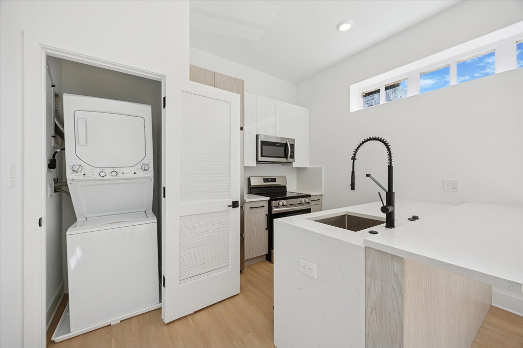 A white kitchen with a sink and a refrigerator.