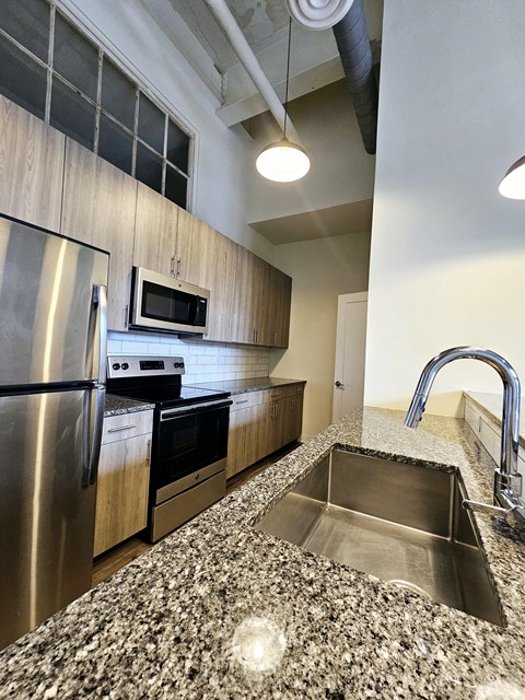A kitchen with a granite counter top and stainless steel appliances.