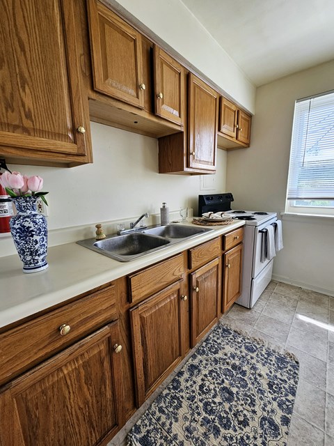 A kitchen with wooden cabinets and a blue and white vase on the counter.