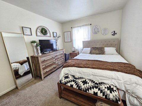 A bedroom with a large bed and a wooden dresser.